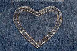 denim heart frame on denim jeans background.  denim heart patch with straight stitch with orange thread, on blue jeans background, text place, copy space. 