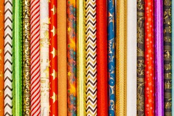 Many different colorful wrapping paper rolls, top view. Holiday gift wrapping papers background