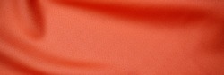 Warm orange silk cloth texture, close up. Red fabric drape background. Red orange background from draped cloth. Coral color Soft silk cloth or satin texture, banner