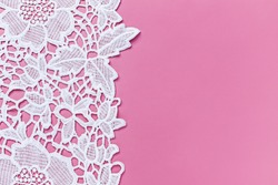 Beautiful white lace cloth on pink background, close up. Copy space. Text place. White lace floral textile fashion pattern. Openwork fabric white lace texture