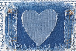 Ripped denim heart frame on Destroyed torn denim blue jeans patch pocket  on white lace background. Denim jeans fashion background