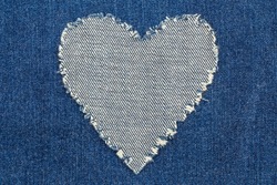 Ripped denim heart frame on denim jeans background. Denim jeans fashion background.