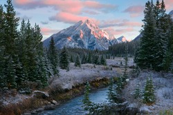 Canadian Rocky Mountain nature scene during a beautiful sunrise with a dusting of overnight snow and frost on the trees and ground. 