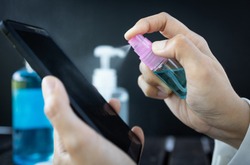 Hand of woman is spraying alcohol,disinfectant spray on mobile phone,prevent infection of Covid-19 virus,contamination of germs or bacteria,wipe or cleaning phone to eliminate,outbreak of Coronavirus