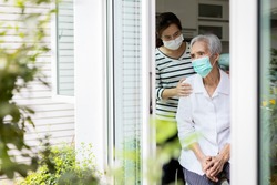 Caregiver woman take care of the elderly,depressed senior is waiting for her family to visit at home,social distancing,nostalgia,stress,life depression,stay home during Covid-19,Coronavirus pandemic  