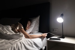 Asian child girl resting on the bed,turning off the light switch before bedtime to sleep in the bedroom at night,turn off lights when not in use,hand turning off lamp,energy power saving , save money
