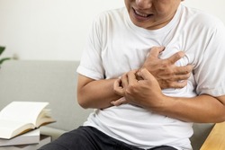 Asian middle-aged man clutching chest pain,difficulty breathing suffer from heart attack,angina pectoris disease,heart and respiration problem,sick male patient feeling chest pain,health care concept