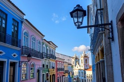 Old facades of colorful colonial-style houses and a tower of an old baroque church in Pelourinho, the famous historic center of Salvador, Bahia