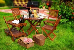 Summer Party or Picnic Scene. Outdoor furniture on the lawn. BBQ Grill in blurred background.