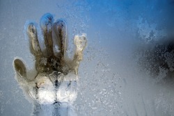 A trace of a hand on a frozen winter window