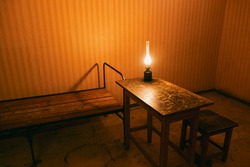 a kerosene lamp on a table in a prison cell