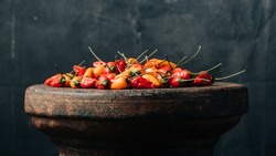Cinematic shot of orange and red habanero peppers on rustic surface with a hand painted black and grey background