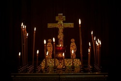 Burning candles with a cross and a crucifix in a Christian church in the dark. Close-up. Faith and religion.