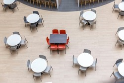 Empty round tables and chairs at a food court in a shopping mall. View from above.