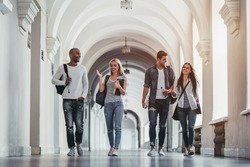 Multiracial students are walking in university hall during break and communicating.