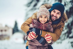 Handsome young dad and his little cute daughter are having fun outdoor in winter. Enjoying spending time together. Family concept.