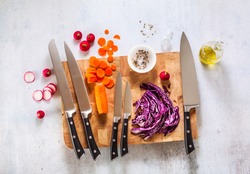 set of new professional kitchen knives on a wooden cutting board and vegetables