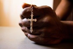 African man's hand holding Cross in prayer 