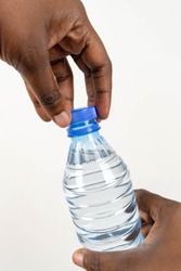 close-up of African American woman opening the plastic cap of water bottle. Black woman's hand opening a screw cap of water bottle isolated on white background for hydration concept