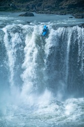 Kayaker reaches the edge of a big waterfall. No turning back