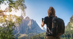 Young Attractive Woman taking a photo With her cellphone hiking in a Beautiful mountain in summer. Discovery Travel Destination Concept