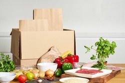 Box with packed meat vegetables on kitchen background. Food delivery services during coronavirus pandemic and social distancing. Shopping online. Dinner delivery service.