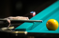 Playing billiard. Player's arm gets ready to stroke a ball with a cue