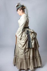 A middle-aged woman in a Victorian costume from the 1870s