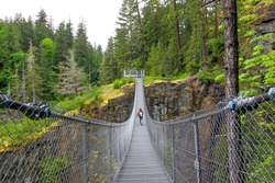 Elk Falls Provincial Park suspension bridge. The view on the hiker walking on the bridge above deep canyon.