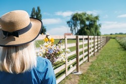 Countryside Getaways, Country vacations, Farm Stays. Young woman in straw hat enjoys summer vacation at the farm in countryside.