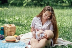Newborn baby spending time outside. Happy and smiling mother with her newborn baby spending time in the park. Getting fresh air and natural sunlight for babies.