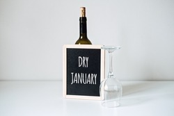 Dry January. Alcohol-free challenge, Health campaign urging people to abstain from alcohol for the January month. Bottle of wine, glass and sign with text Dry January
