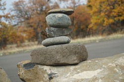 Sloped hill  behind stacked stones showing gravity pointing up and peaceful balance in quiet autumn scene