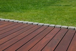 Teak wood deck detail next green grass, natural exotic hardwood lumber outdoor flooring