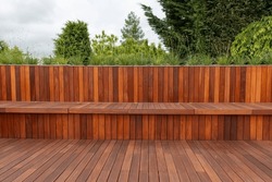 Wood fence cladding and decking, garden greenery on the background
