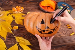 A big painted halloween pumpkin with leaves on a wooden background. Halloween concept