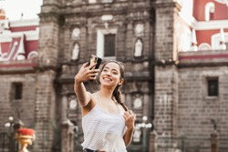 Selfie Portrait of a young latin woman in the street with a smartphone in Mexico