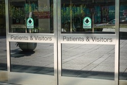 Automatic sliding glass door entrance to a hospital that says patients and visitors