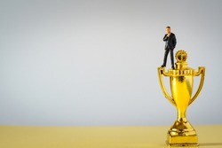 miniture businessman on gold Trophies on white background
