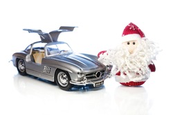 Santa Claus or Father Frost with old vintage automobile on white background with reflection. Main focus of image on Santa Claus and selective on turned right and opened doors toy retro car