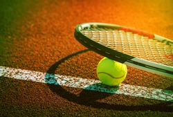 Sport background design dark tone. Closeup tennis ball and racket on line point on clay court.