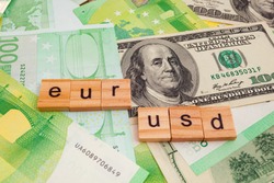 USD EUR inscription on wooden cubes on the texture of us dollars and euro banknotes