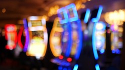 Defocused slot machines glow in casino on fabulous Las Vegas Strip, USA. Blurred gambling jackpot slots in hotel near Fremont street. Illuminated neon fruit machine for risk money playing and betting.