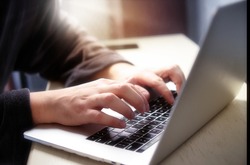 Hand typing on computer keyboard. Male hands with laptop. Man in a housecoat working remote at home. Online courses. With blur and shallow depth of field
