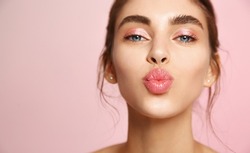 Cosmetics and skin care. Portrait of beautiful woman pucker lips, kissing, showing natural clean facial skin, standing over pink background