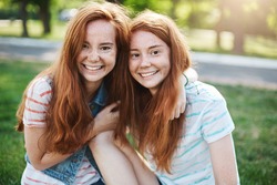 Portrait of identical ginger twin sisters smiling and having fun. Red haired rascals taking the best of their life. Friendship and youth concept.