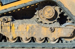 close up of bulldozer gears and track caked with mud