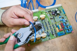 an electric technician with an electronic board performing maintenance as part of a skilled job workforce in the electric power and electronic industry