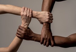 Races united against discrimination and racism. Black African American and Caucasian hands holding together in world unity and racial love and understanding. Tolerance and cooperation concept.