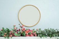 Round gold mirror on the wall above the fireplace. Flower multicolored installation 